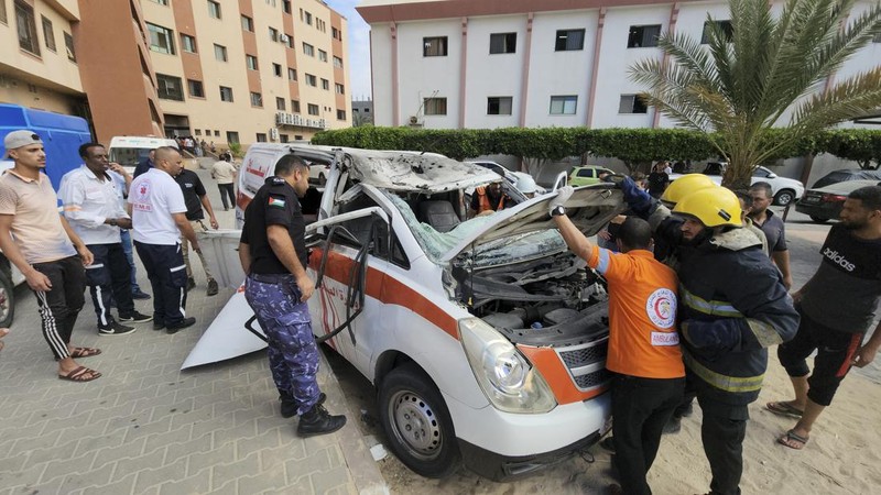 Palestinian medics inspect a damaged Ambulance hit by an Israeli air strike inside Nasser Hospital in Khan Younis, southern Gaza Strip, Saturday, Oct. 7, 2023. The militant Hamas rulers of the Gaza Strip carried out an unprecedented, multi-front attack on Israel at daybreak Saturday, firing thousands of rockets as dozens of Hamas fighters infiltrated the heavily fortified border in several locations by air, land, and sea and catching the country off-guard on a major holiday. (AP Photo/Hassan Eslaiah)