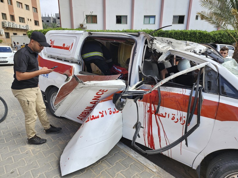 Palestinian medics inspect a damaged Ambulance hit by an Israeli air strike inside Nasser Hospital in Khan Younis, southern Gaza Strip, Saturday, Oct. 7, 2023. The militant Hamas rulers of the Gaza Strip carried out an unprecedented, multi-front attack on Israel at daybreak Saturday, firing thousands of rockets as dozens of Hamas fighters infiltrated the heavily fortified border in several locations by air, land, and sea and catching the country off-guard on a major holiday. (AP Photo/Hassan Eslaiah)