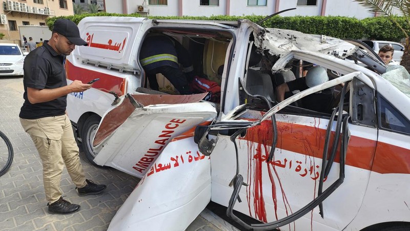 Palestinian medics inspect a damaged Ambulance hit by an Israeli air strike inside Nasser Hospital in Khan Younis, southern Gaza Strip, Saturday, Oct. 7, 2023. The militant Hamas rulers of the Gaza Strip carried out an unprecedented, multi-front attack on Israel at daybreak Saturday, firing thousands of rockets as dozens of Hamas fighters infiltrated the heavily fortified border in several locations by air, land, and sea and catching the country off-guard on a major holiday. (AP Photo/Hassan Eslaiah)