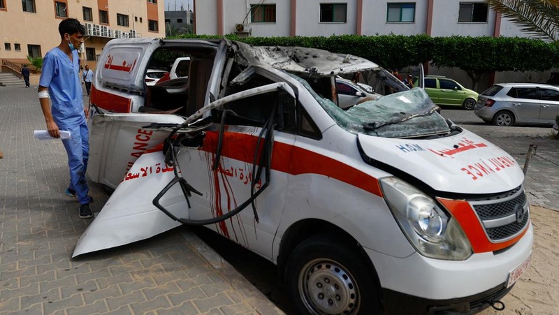 Palestinian medics inspect a damaged Ambulance hit by an Israeli air strike inside Nasser Hospital in Khan Younis, southern Gaza Strip, Saturday, Oct. 7, 2023. The militant Hamas rulers of the Gaza Strip carried out an unprecedented, multi-front attack on Israel at daybreak Saturday, firing thousands of rockets as dozens of Hamas fighters infiltrated the heavily fortified border in several locations by air, land, and sea and catching the country off-guard on a major holiday. (AP Photo/Hassan Eslaiah)