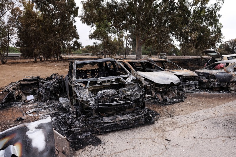 ISRAEL-PALESTINIANS/GAZA Israeli soldiers inspect burnt cars that are abandoned in a carpark near where a festival was held before an attack by Hamas gunmen from Gaza that left at least 260 people dead, by Israel's border with Gaza in southern Israel, October 10, 2023. REUTERS/Ronen Zvulun