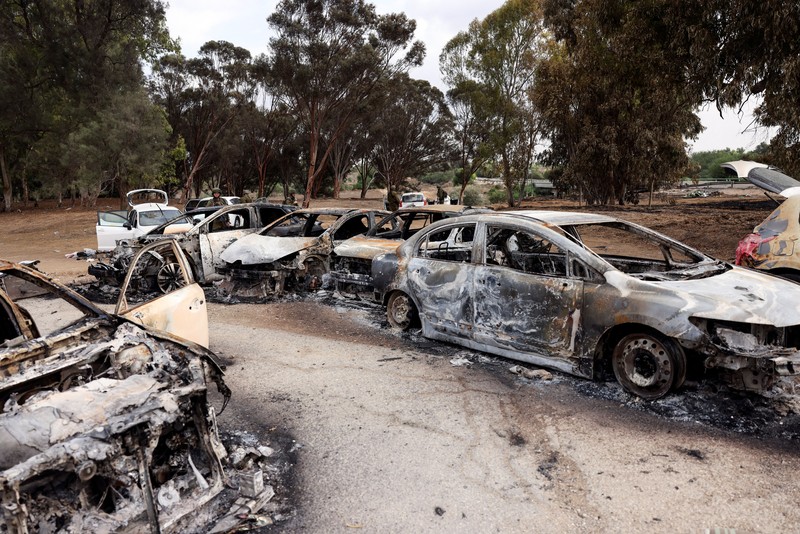 ISRAEL-PALESTINIANS/GAZA Israeli soldiers inspect burnt cars that are abandoned in a carpark near where a festival was held before an attack by Hamas gunmen from Gaza that left at least 260 people dead, by Israel's border with Gaza in southern Israel, October 10, 2023. REUTERS/Ronen Zvulun