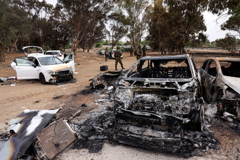 ISRAEL-PALESTINIANS/GAZA Israeli soldiers inspect burnt cars that are abandoned in a carpark near where a festival was held before an attack by Hamas gunmen from Gaza that left at least 260 people dead, by Israel's border with Gaza in southern Israel, October 10, 2023. REUTERS/Ronen Zvulun