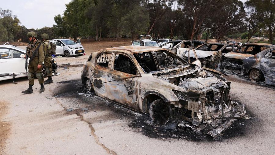 Israeli soldiers inspect burnt cars that are abandoned in a carpark near where a festival was held before an attack by Hamas gunmen from Gaza that left at least 260 people dead, by Israel's border with Gaza in southern Israel, October 10, 2023. REUTERS/Ronen Zvulun