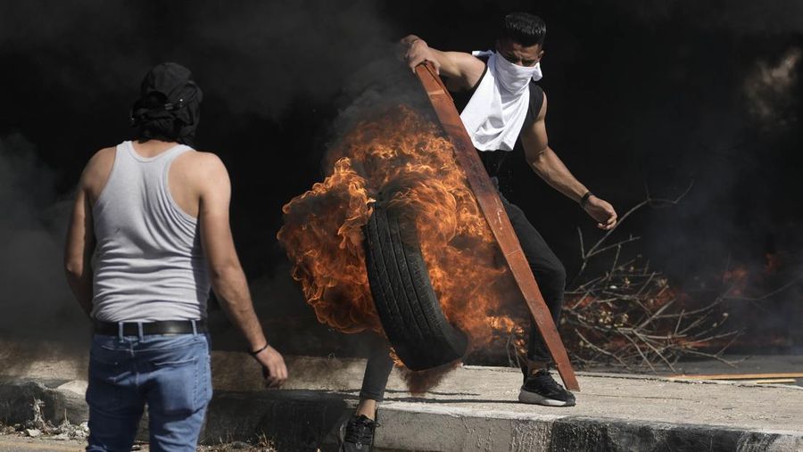 Para pengunjuk rasa membakar ban ketika warga Palestina mengambil bagian dalam protes menyusul serangan Israel di Gaza. (REUTERS/Mussa Qawasma)