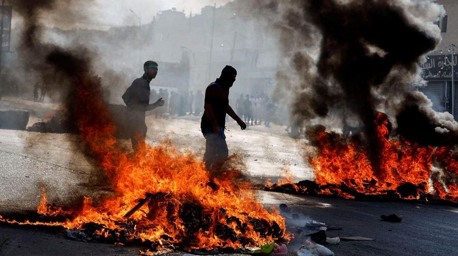Para pengunjuk rasa membakar ban ketika warga Palestina mengambil bagian dalam protes menyusul serangan Israel di Gaza. (REUTERS/Mussa Qawasma)