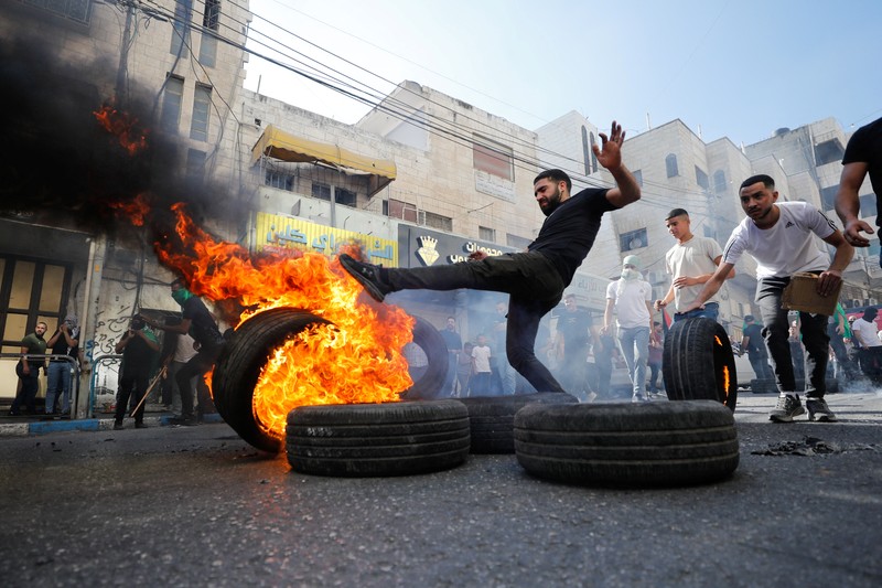 Para pengunjuk rasa membakar ban ketika warga Palestina mengambil bagian dalam protes menyusul serangan Israel di Gaza. (REUTERS/Mussa Qawasma) Para pengunjuk rasa membakar ban ketika warga Palestina mengambil bagian dalam protes menyusul serangan Israel di Gaza. (REUTERS/Mussa Qawasma)
