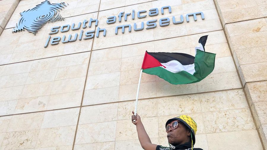 Seorang wanita memegang bendera Palestina di luar Museum Yahudi Afrika Selatan saat protes untuk menyatakan dukungan kepada rakyat Palestina, di Cape Town, Afrika Selatan, 11 Oktober 2023. (REUTERS/Esa Alexander)