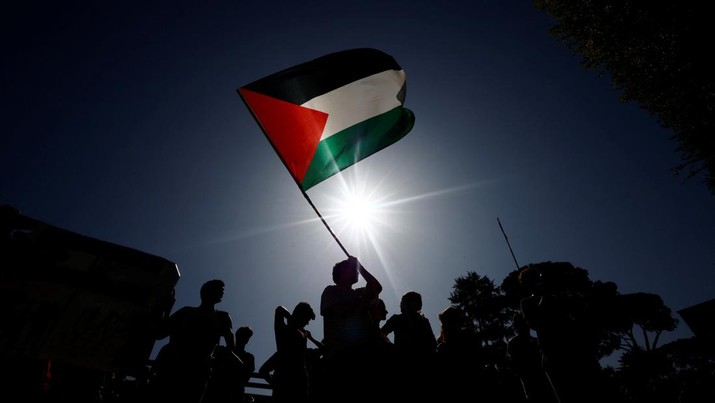 Seseorang memegang bendera Palestina saat mahasiswa berdemonstrasi untuk menyatakan dukungan kepada rakyat Palestina dalam protes di Universitas La Sapienza, di Roma, 10 Oktober 2023. (REUTERS/Yara Nardi)