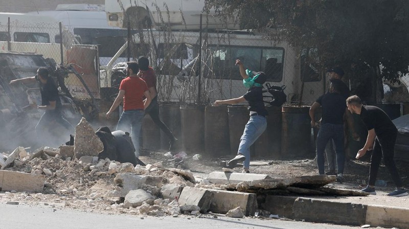 Para pengunjuk rasa membakar ban ketika warga Palestina mengambil bagian dalam protes menyusul serangan Israel di Gaza. (REUTERS/Mussa Qawasma)