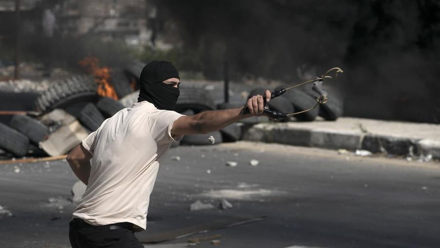 Warga Palestina menggunakan ketapel untuk melawan pasukan Israel di tepi barat jalur Gaza. (AP/Majdi Mohammed)