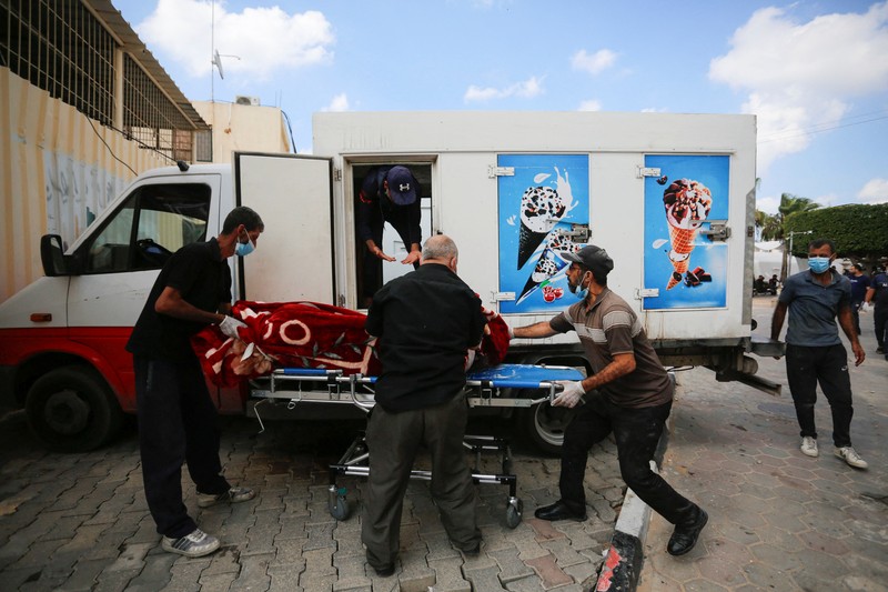 Orang-orang membawa jenazah seorang warga Palestina, yang tewas dalam serangan Israel, dari truk es krim tempatnya disimpan, saat kamar mayat rumah sakit penuh sesak, di tengah konflik Israel-Palestina yang sedang berlangsung, di Jalur Gaza tengah, 15 Oktober 2023. Orang-orang membawa jenazah seorang warga Palestina, yang tewas dalam serangan Israel, dari truk es krim tempatnya disimpan, saat kamar mayat rumah sakit penuh sesak, di tengah konflik Israel-Palestina yang sedang berlangsung, di Jalur Gaza tengah, 15 Oktober 2023. (REUTERS/Stringer)