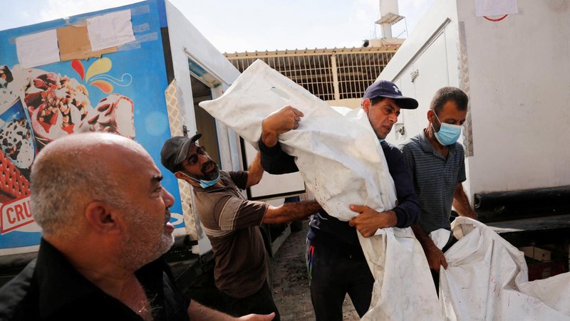 Orang-orang membawa jenazah seorang warga Palestina, yang tewas dalam serangan Israel, dari truk es krim tempatnya disimpan, saat kamar mayat rumah sakit penuh sesak, di tengah konflik Israel-Palestina yang sedang berlangsung, di Jalur Gaza tengah, 15 Oktober 2023. (REUTERS/Stringer)