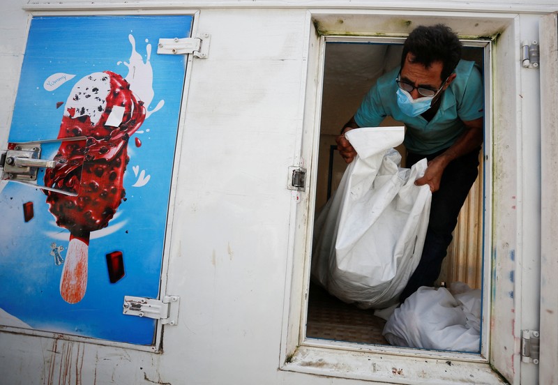 Orang-orang membawa jenazah seorang warga Palestina, yang tewas dalam serangan Israel, dari truk es krim tempatnya disimpan, saat kamar mayat rumah sakit penuh sesak, di tengah konflik Israel-Palestina yang sedang berlangsung, di Jalur Gaza tengah, 15 Oktober 2023. Orang-orang membawa jenazah seorang warga Palestina, yang tewas dalam serangan Israel, dari truk es krim tempatnya disimpan, saat kamar mayat rumah sakit penuh sesak, di tengah konflik Israel-Palestina yang sedang berlangsung, di Jalur Gaza tengah, 15 Oktober 2023. (REUTERS/Stringer)