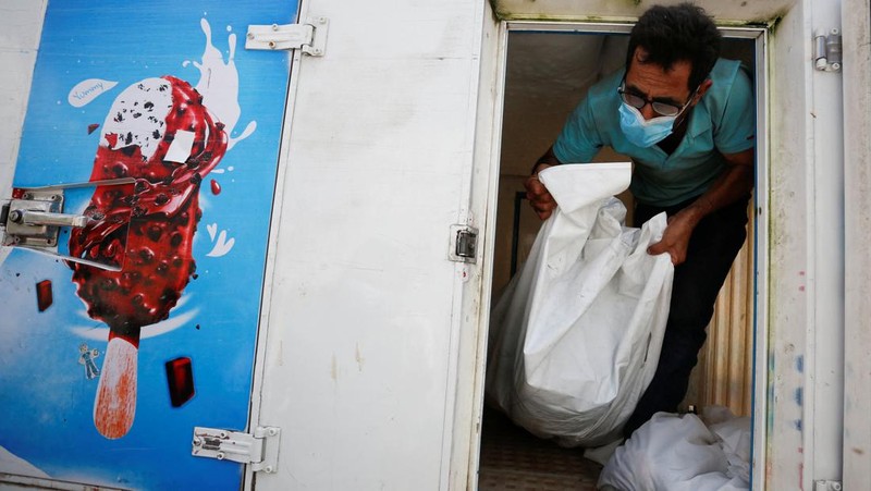 Orang-orang membawa jenazah seorang warga Palestina, yang tewas dalam serangan Israel, dari truk es krim tempatnya disimpan, saat kamar mayat rumah sakit penuh sesak, di tengah konflik Israel-Palestina yang sedang berlangsung, di Jalur Gaza tengah, 15 Oktober 2023. (REUTERS/Stringer)