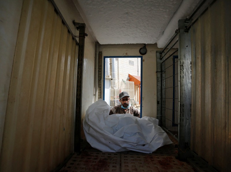 Orang-orang membawa jenazah seorang warga Palestina, yang tewas dalam serangan Israel, dari truk es krim tempatnya disimpan, saat kamar mayat rumah sakit penuh sesak, di tengah konflik Israel-Palestina yang sedang berlangsung, di Jalur Gaza tengah, 15 Oktober 2023. Orang-orang membawa jenazah seorang warga Palestina, yang tewas dalam serangan Israel, dari truk es krim tempatnya disimpan, saat kamar mayat rumah sakit penuh sesak, di tengah konflik Israel-Palestina yang sedang berlangsung, di Jalur Gaza tengah, 15 Oktober 2023. (REUTERS/Stringer)