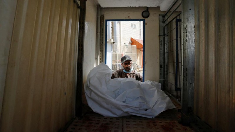 Orang-orang membawa jenazah seorang warga Palestina, yang tewas dalam serangan Israel, dari truk es krim tempatnya disimpan, saat kamar mayat rumah sakit penuh sesak, di tengah konflik Israel-Palestina yang sedang berlangsung, di Jalur Gaza tengah, 15 Oktober 2023. (REUTERS/Stringer)