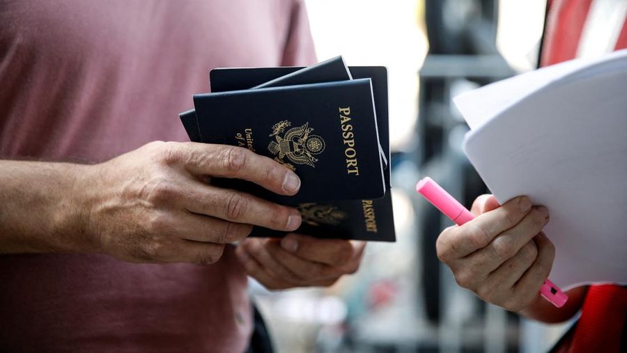 Seorang pria memegang setumpuk paspor AS ketika warga negara AS dan anggota keluarga dekat mereka menunggu sebelum meninggalkan Israel dengan kapal menuju Siprus, di tengah konflik yang sedang berlangsung antara Israel dan kelompok Islam Palestina Hamas, di Haifa, Israel, 16 Oktober 2023. (REUTERS/Shir Torem)