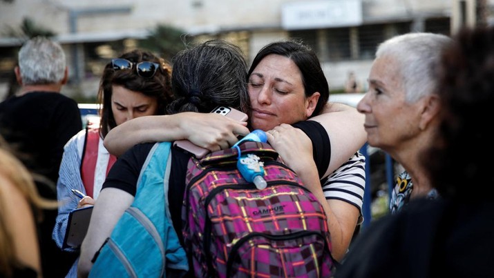 Wanita berpelukan saat warga negara AS dan anggota keluarga dekat mereka menunggu sebelum meninggalkan Israel dengan kapal menuju Siprus, di tengah konflik yang sedang berlangsung antara Israel dan kelompok Islam Palestina Hamas, di Haifa, Israel, 16 Oktober 2023. (REUTERS/Shir Torem)