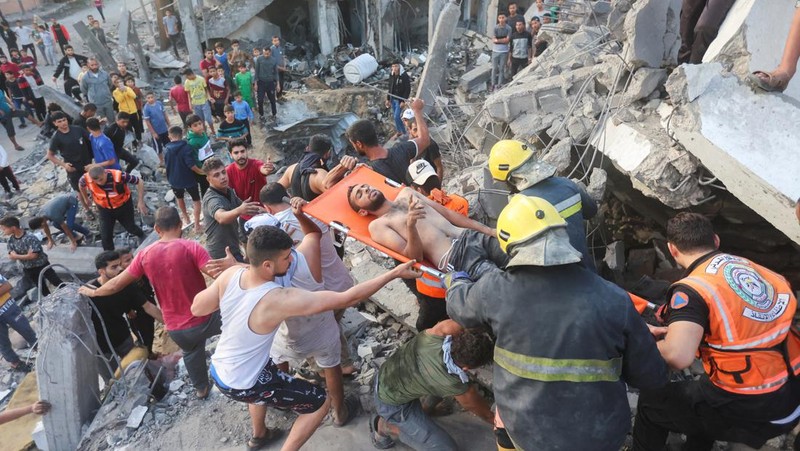 Orang-orang berkumpul saat warga Palestina berupaya mengeluarkan korban dari bawah reruntuhan rumah yang hancur akibat serangan Israel, di Khan Younis di selatan Jalur Gaza 17 Oktober 2023. (REUTERS/Ahmed Zakot)
