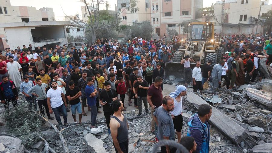 Orang-orang berkumpul saat warga Palestina berupaya mengeluarkan korban dari bawah reruntuhan rumah yang hancur akibat serangan Israel, di Khan Younis di selatan Jalur Gaza 17 Oktober 2023. (REUTERS/Ahmed Zakot)