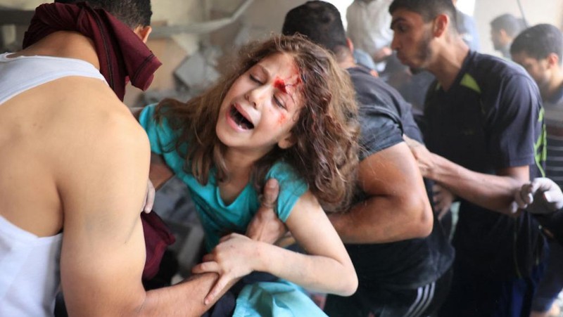 Orang-orang berkumpul saat warga Palestina berupaya mengeluarkan korban dari bawah reruntuhan rumah yang hancur akibat serangan Israel, di Khan Younis di selatan Jalur Gaza 17 Oktober 2023. (REUTERS/Ahmed Zakot)