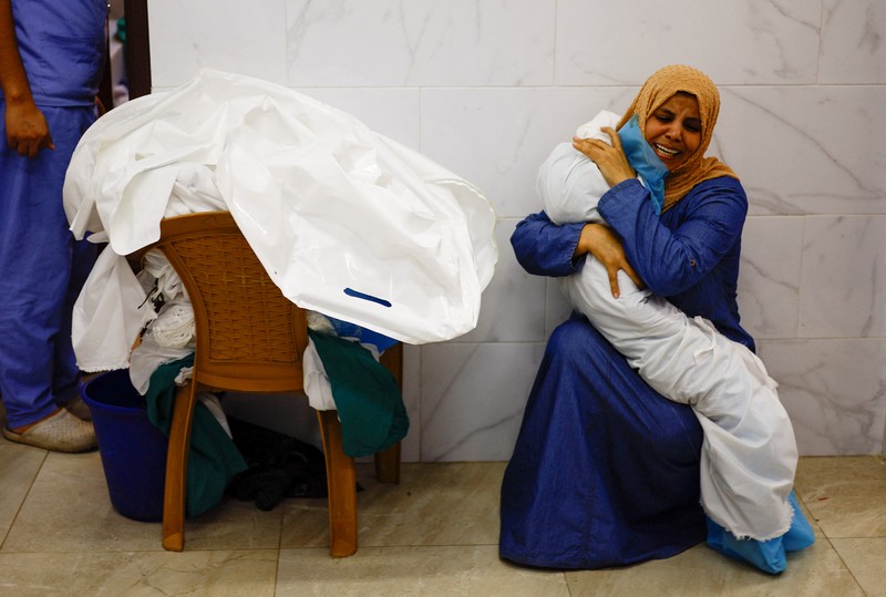 Seorang wanita memeluk jenazah seorang anak Palestina yang tewas dalam serangan Israel, di sebuah rumah sakit di Khan Younis di Jalur Gaza selatan, 17 Oktober 2023. (REUTERS/Mohammed Salem)