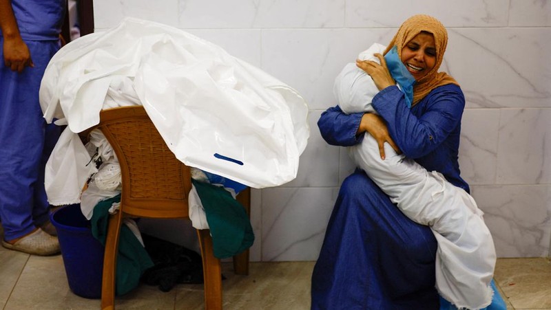Seorang wanita memeluk jenazah seorang anak Palestina yang tewas dalam serangan Israel, di sebuah rumah sakit di Khan Younis di Jalur Gaza selatan, 17 Oktober 2023. (REUTERS/Mohammed Salem)
