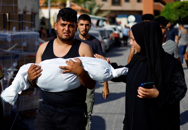 Seorang wanita memeluk jenazah seorang anak Palestina yang tewas dalam serangan Israel, di sebuah rumah sakit di Khan Younis di Jalur Gaza selatan, 17 Oktober 2023. (REUTERS/Mohammed Salem)