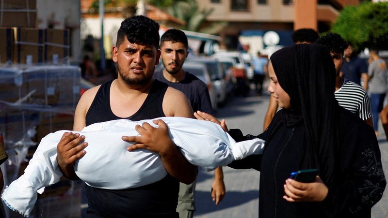 Seorang wanita memeluk jenazah seorang anak Palestina yang tewas dalam serangan Israel, di sebuah rumah sakit di Khan Younis di Jalur Gaza selatan, 17 Oktober 2023. (REUTERS/Mohammed Salem)