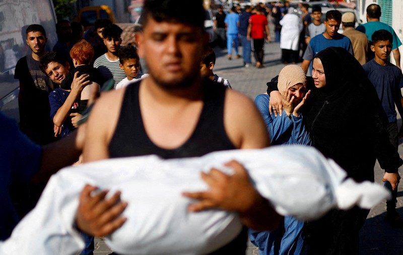 Seorang wanita memeluk jenazah seorang anak Palestina yang tewas dalam serangan Israel, di sebuah rumah sakit di Khan Younis di Jalur Gaza selatan, 17 Oktober 2023. (REUTERS/Mohammed Salem)