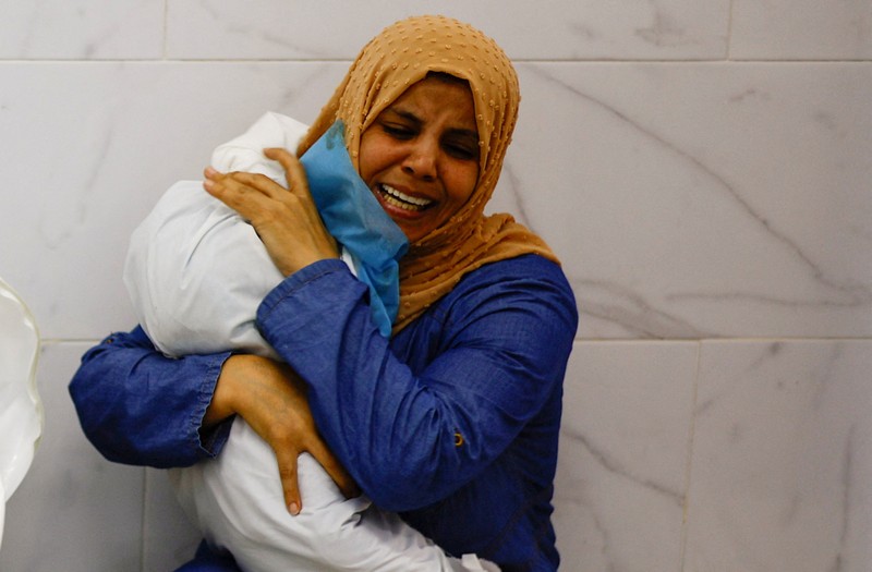 Seorang wanita memeluk jenazah seorang anak Palestina yang tewas dalam serangan Israel, di sebuah rumah sakit di Khan Younis di Jalur Gaza selatan, 17 Oktober 2023. (REUTERS/Mohammed Salem)