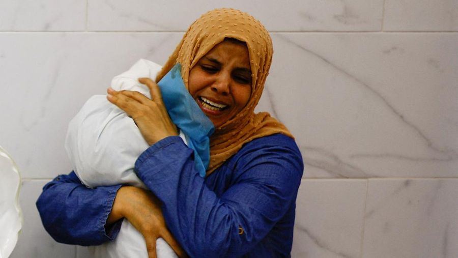 Seorang warga menolong anak yang tertimpa reruntuhan bangunan akibat serangan udara Israel di Jalur Gaza. (REUTERS/Mohammed Salem)
