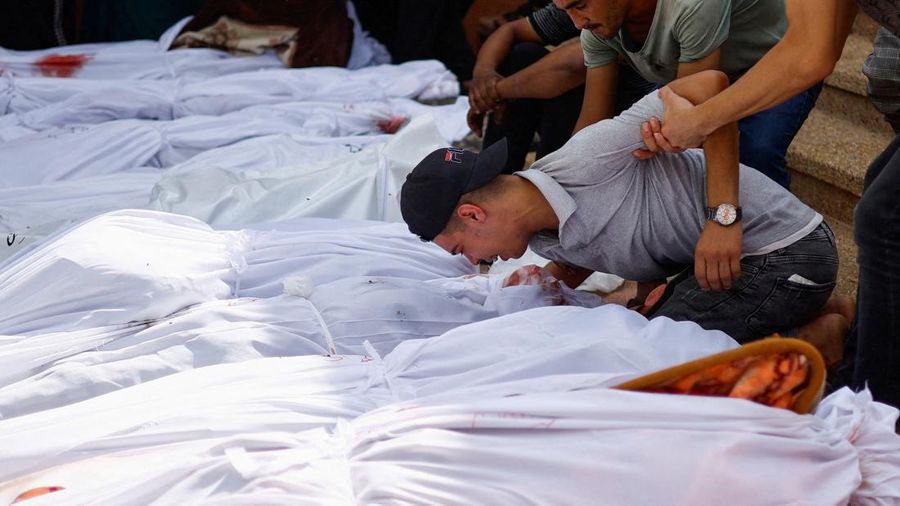 Seorang warga menolong anak yang tertimpa reruntuhan bangunan akibat serangan udara Israel di Jalur Gaza. (REUTERS/Mohammed Salem)