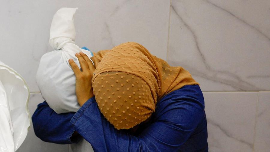 Seorang wanita memeluk jenazah seorang anak Palestina yang tewas dalam serangan Israel, di sebuah rumah sakit di Khan Younis di Jalur Gaza selatan, 17 Oktober 2023. (REUTERS/Mohammed Salem)