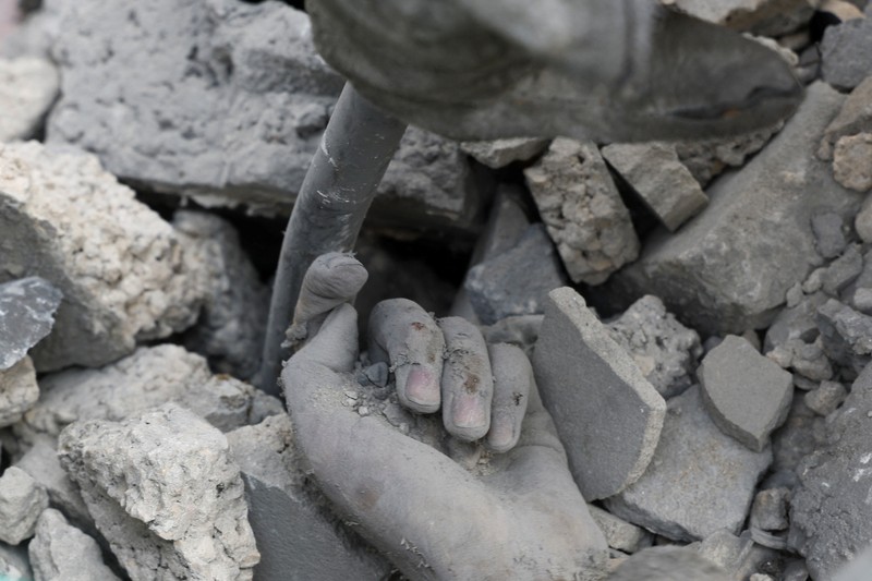Seorang warga menolong anak yang tertimpa reruntuhan bangunan akibat serangan udara Israel di Jalur Gaza. (REUTERS/Mohammed Salem)