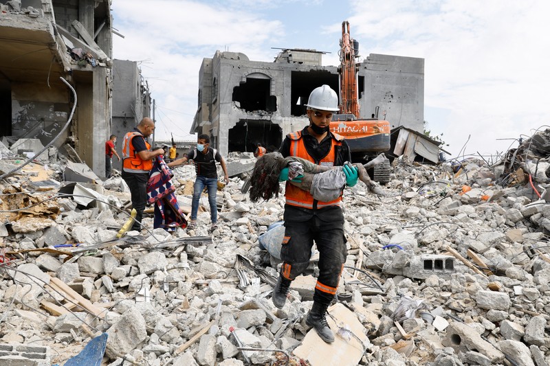 Seorang warga menolong anak yang tertimpa reruntuhan bangunan akibat serangan udara Israel di Jalur Gaza. (REUTERS/Mohammed Salem)