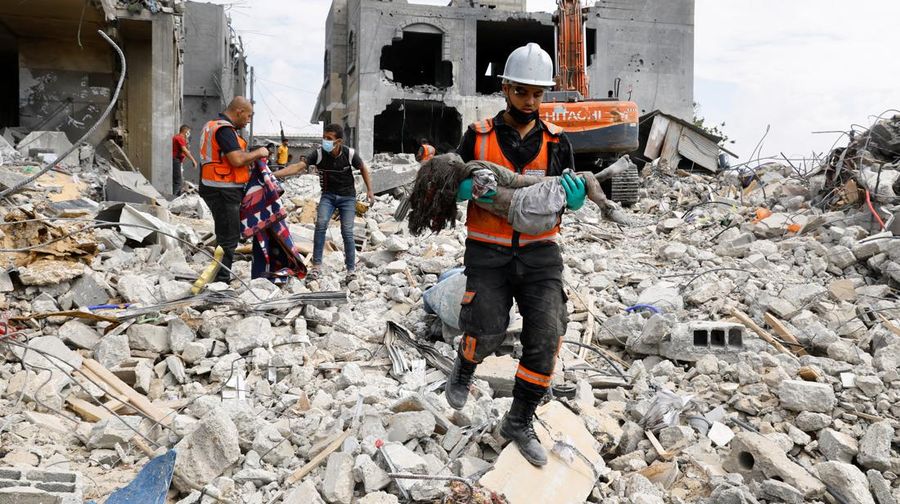Seorang warga menolong anak yang tertimpa reruntuhan bangunan akibat serangan udara Israel di Jalur Gaza. (REUTERS/Mohammed Salem)