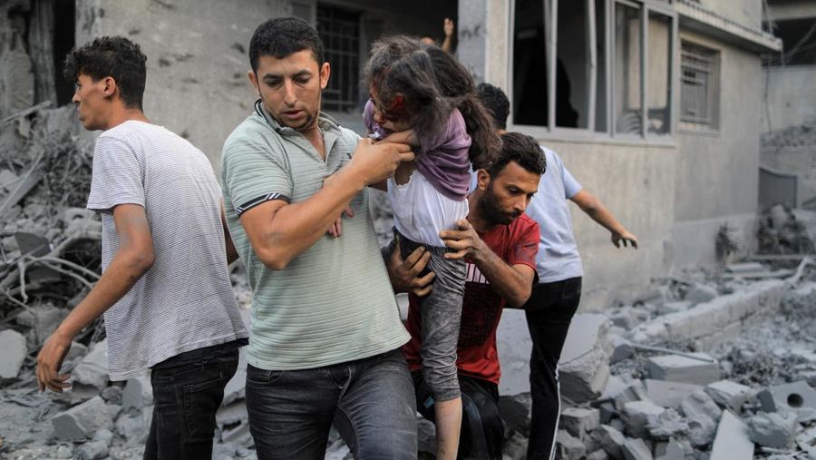 Seorang warga menolong anak yang tertimpa reruntuhan bangunan akibat serangan udara Israel di Jalur Gaza. (REUTERS/Mohammed Salem)