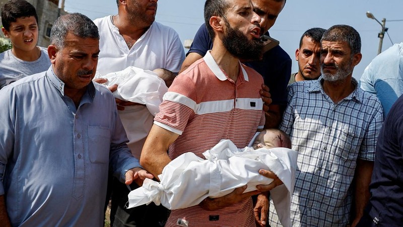 Seorang warga menolong anak yang tertimpa reruntuhan bangunan akibat serangan udara Israel di Jalur Gaza. (REUTERS/Mohammed Salem)