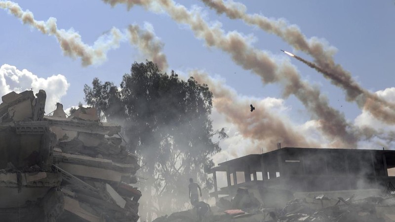 Rockets are fired from the Gaza Strip toward Israel over destroyed buildings following Israeli airstrikes on Gaza City, central Gaza Strip, Thursday, Oct. 19, 2023. (AP Photo/Mohammed Dahman)
