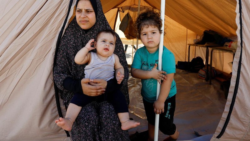 Warga Palestina, yang meninggalkan rumah mereka di tengah serangan Israel, berlindung di tenda kamp di sebuah pusat yang dikelola PBB, setelah Israel menyerukan agar lebih dari 1 juta warga sipil di Gaza utara untuk pindah ke selatan, di Khan Younis di Jalur Gaza selatan, Oktober 19 Agustus 2023. REUTERS/Ibraheem Abu Mustafa