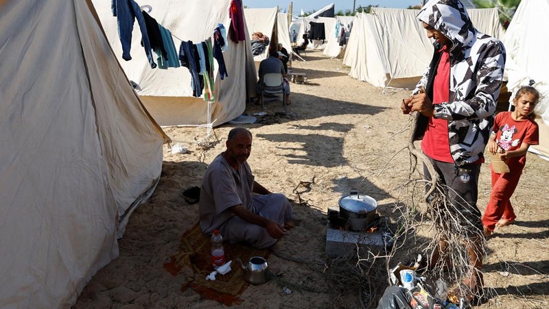 Warga Palestina, yang meninggalkan rumah mereka di tengah serangan Israel, berlindung di tenda kamp di sebuah pusat yang dikelola PBB, setelah Israel menyerukan agar lebih dari 1 juta warga sipil di Gaza utara untuk pindah ke selatan, di Khan Younis di Jalur Gaza selatan, Oktober 19 Agustus 2023. REUTERS/Ibraheem Abu Mustafa
