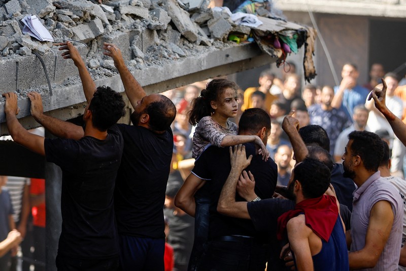 Warga Palestina berkumpul di lokasi serangan Israel terhadap sebuah rumah di Khan Younis, di Jalur Gaza selatan, 24 Oktober 2023. (REUTERS/Mohammed Salem)
