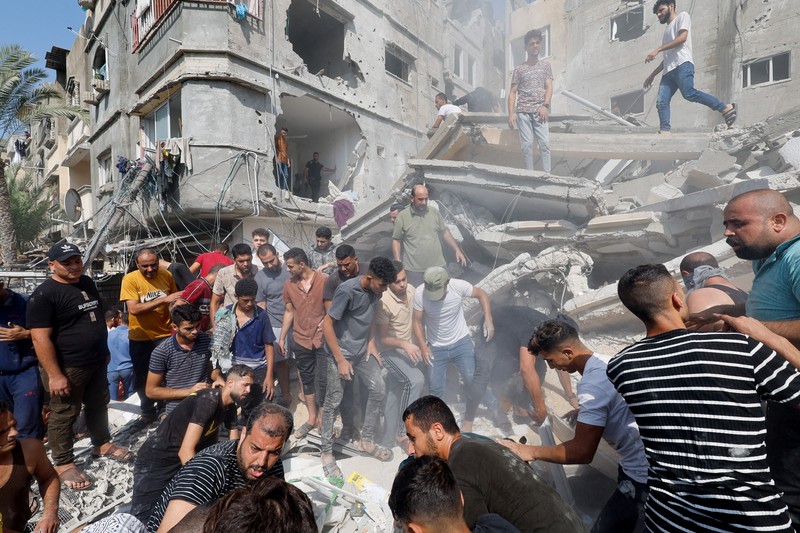 Warga Palestina berkumpul di lokasi serangan Israel terhadap sebuah rumah di Khan Younis, di Jalur Gaza selatan, 24 Oktober 2023. (REUTERS/Mohammed Salem)