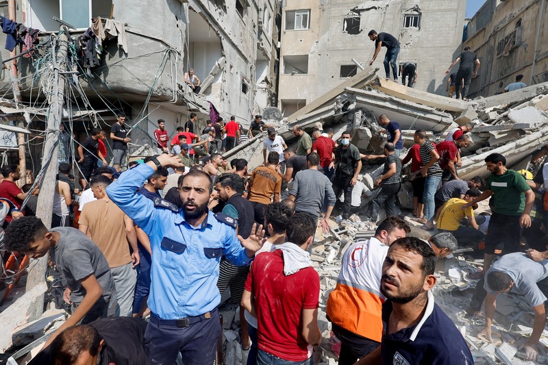 Warga Palestina berkumpul di lokasi serangan Israel terhadap sebuah rumah di Khan Younis, di Jalur Gaza selatan, 24 Oktober 2023. (REUTERS/Mohammed Salem)
