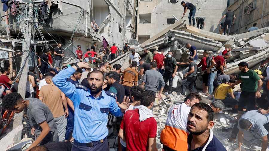 Warga Palestina berkumpul di lokasi serangan Israel terhadap sebuah rumah di Khan Younis, di Jalur Gaza selatan, 24 Oktober 2023. (REUTERS/Mohammed Salem)