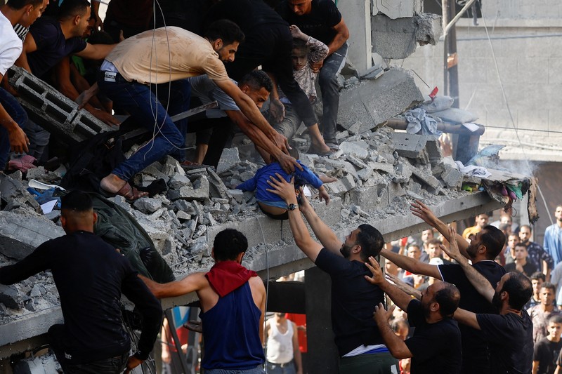 Warga Palestina berkumpul di lokasi serangan Israel terhadap sebuah rumah di Khan Younis, di Jalur Gaza selatan, 24 Oktober 2023. (REUTERS/Mohammed Salem)