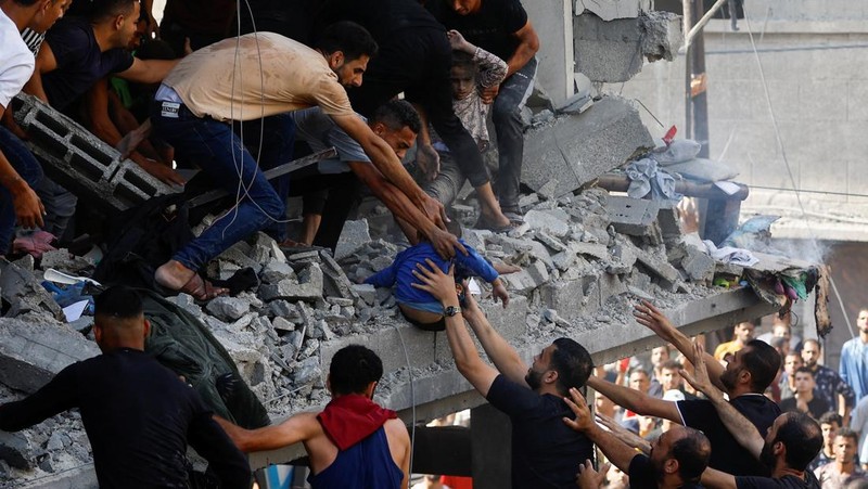 Warga Palestina berkumpul di lokasi serangan Israel terhadap sebuah rumah di Khan Younis, di Jalur Gaza selatan, 24 Oktober 2023. (REUTERS/Mohammed Salem)