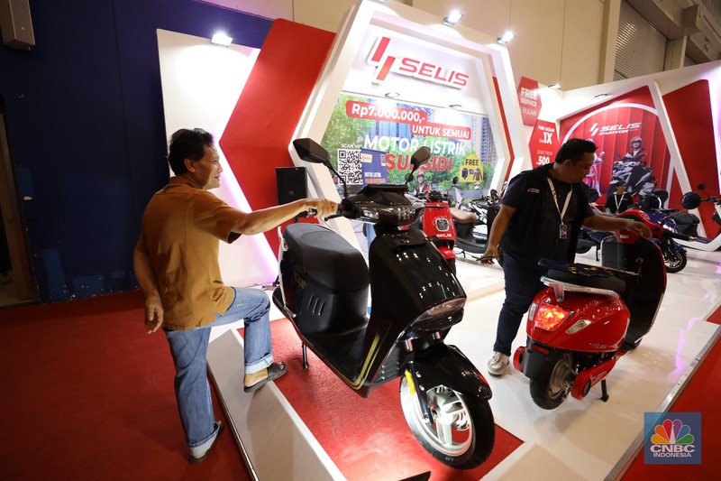 Pengunjung melihat motor listrik dalam ameran Indonesia Motorcycles Show atau IMOS+ 2023 di ICE BSD, Tangerang, Rabu (25/10/2023). (CNBC Indonesia/Tri Susilo)